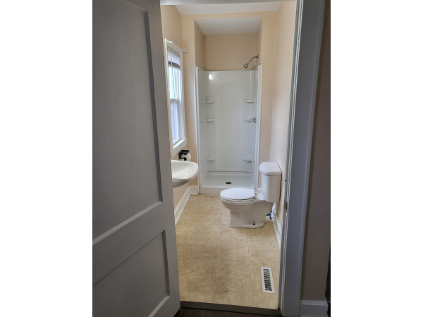 Bathroom with Foyer area nearby with space for Desk near access to large basement that has laundry area and tons of storage or workshop.